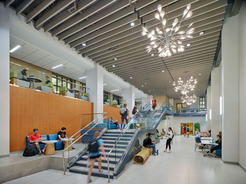Grand stair and collaboration space at Penn State University Pattee Library Knowledge Commons featuring decorative lighting, integrated architectural illumination, and open student gathering areas.