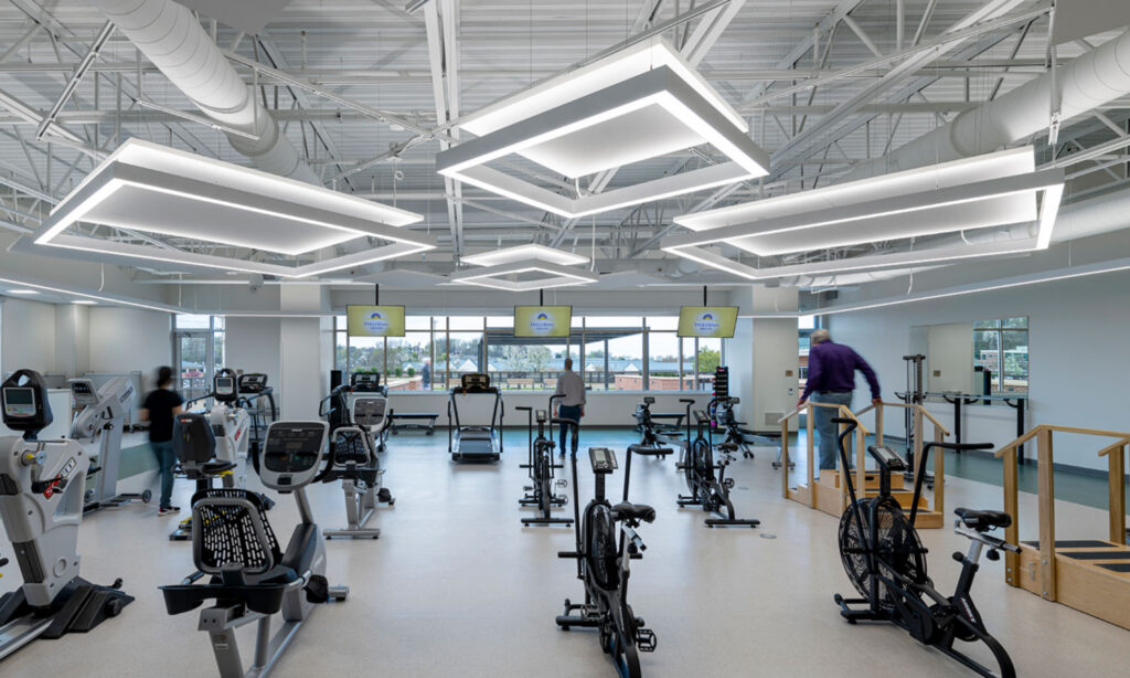 Cardiac rehabilitation gym at the WellSpan Health Heart & Vascular Center featuring geometric architectural lighting, exercise equipment, and a bright patient wellness environment.
